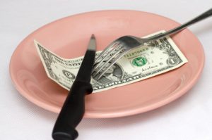 One dollar on a plate with a knife and fork.